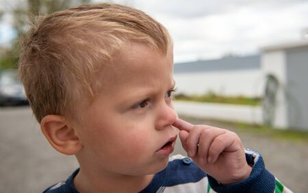 a baby boy is picking her nose with finger inside