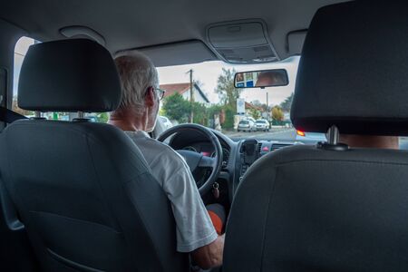 a senior man driving car, wide angle interior view