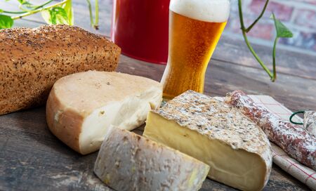 cheeses and Tomme de Savoie with a glass of beer, French cheese Savoy, french Alps France.の写真素材