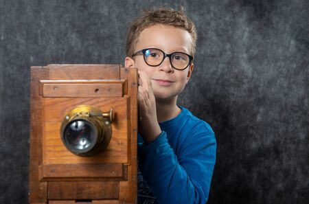 cheerful boy retro photographer with a vintage wooden cameraの写真素材