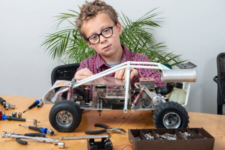 a little boy repairing a model radio-controlled car at home
