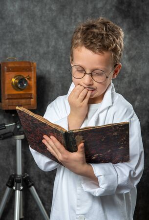 cheerful boy retro with a white blouse reading a bookの写真素材