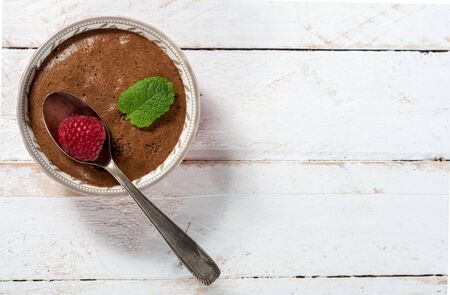 Homemade chocolate mousse with  raspberry on the white wooden background