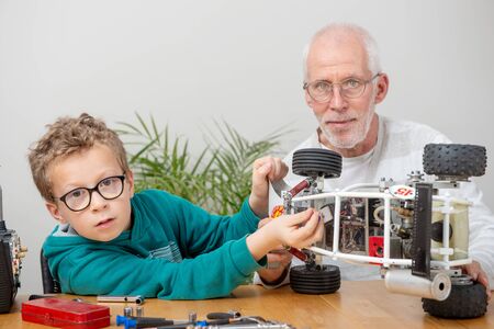 Grandpa and son little boy repairing a  model radio-controlled car at home