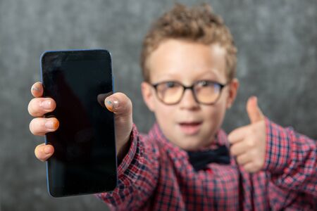 Little boy showing a smartphone black blank screenの写真素材