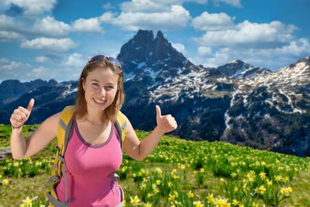 Pretty hiker woman with Pic du Midi Ossau and daffodils in springtime, french Pyreneesの写真素材