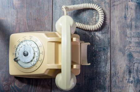 A beige old telephone on the wooden