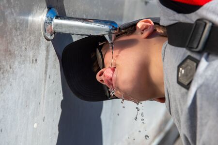 child drinks from tap, outdoorの写真素材
