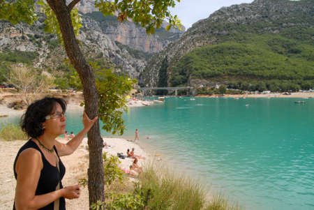 pretty mature brunette woman and a lake on backgroundの写真素材