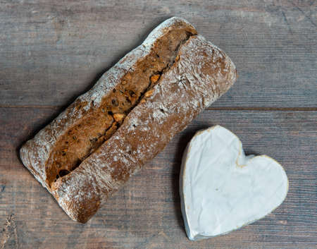 a French Neufchatel cheese shaped heart on wooden background