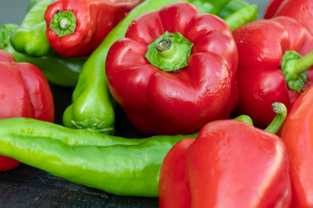 red and green organic peppers on a black tableの写真素材