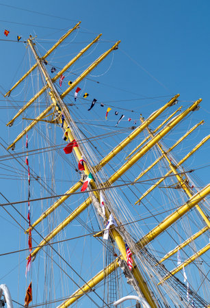 the masts of a wooden tall sailboat with flags