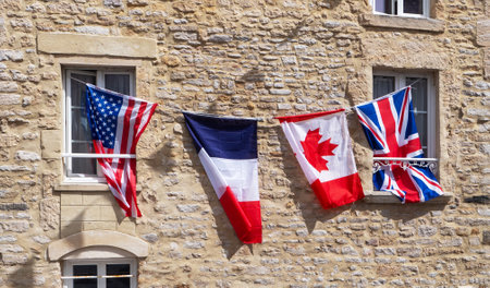 Four flags hanging from a window, including the American, British, French, and Canadian flagsの写真素材