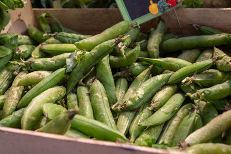 A box of green peas is displayed in a market. The peas are fresh and ready to be eatenの写真素材