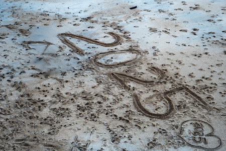A beach with a large footprint in the sand that says "2025". The footprint is large and covers a significant portion of the sandの写真素材