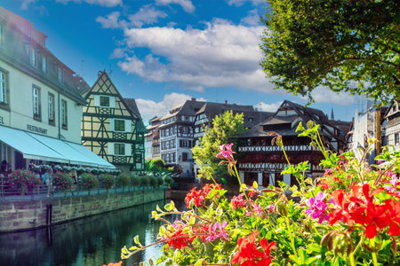 A beautiful city with a river running through it and a lot of flowers. The flowers are red and pink and are in a garden. Strasbourg, Franceの写真素材