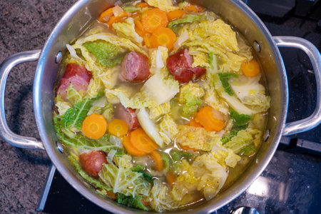 A pot of soup with vegetables and meat in it. The soup is hot and bubbling. The vegetables include carrots and cabbageの写真素材