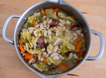 A large pot of soup with beans, carrots, and cabbage. The soup is full and has a lot of ingredientsの写真素材