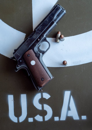 Gun with a few bullets on a table next to a sign that says USA. Scene is tense and serious