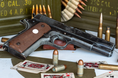 a gun is on a table with a pile of bullets. The gun is a Colt 45. Scene is tense and dangerousの写真素材