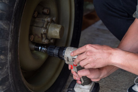 Man is using a tool to fix a tire. Concept of determination and focus as the man works to repair the tireの写真素材