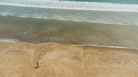 Aerial view of a woman walking on the beach at sunset.の写真素材