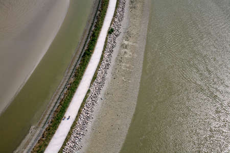 Dike with people who ride a bicycleの写真素材