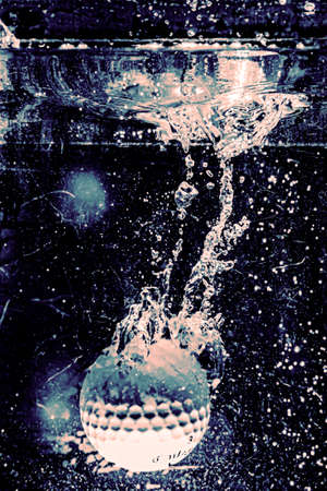 golf ball falling into waterの写真素材