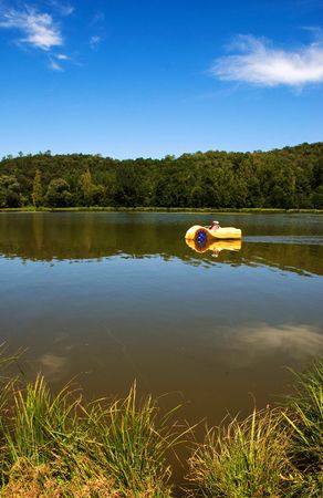 Yellow pedalo on lake, blue sky, portrait formatの写真素材