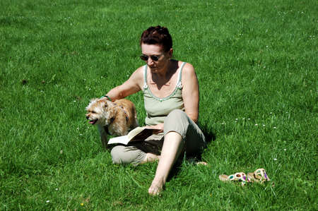 Lady reading in a book and playing with her dogの写真素材