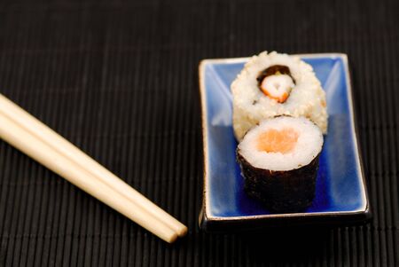 Chopsticks and sushi rolls on black matの写真素材