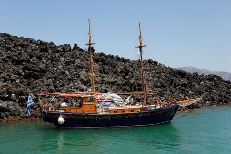 Traditional sailing boat anchored at the island Nea Kameni in Santorini, Greece