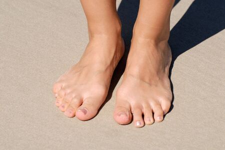 Feet of a young woman standing on the beach