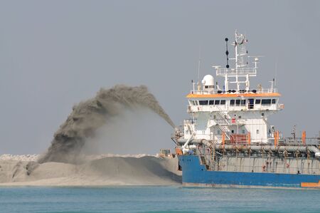 Special dredge ship pipe pushing sand to create new land in Dubai, United Arab Emiratesの写真素材