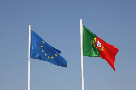 Portuguese and European flags against blue skyの写真素材