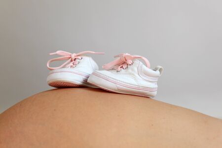 Little baby shoes on pregnant bellyの写真素材