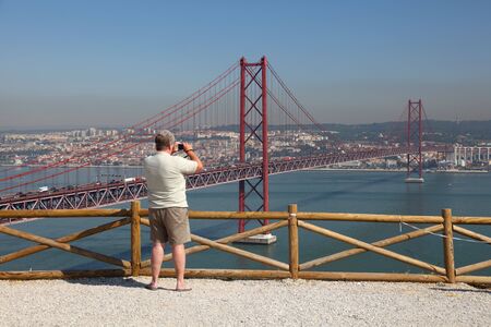 Tourist taking pictures of the Ponte 25 de Abril - Suspension bridge over the Tagus river in Lisbon, Portugal. Photo taken at 30th of June 2010のeditorial素材