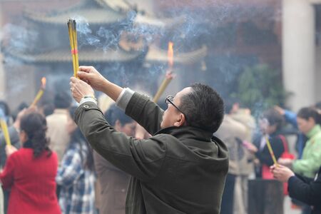 Praying Person with Incense Sticks at Buddhist temple in Shanghai, China. Photo taken at 20th of November 2010のeditorial素材