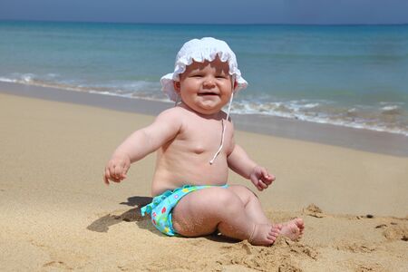 Little baby girl sitting on the beachの写真素材
