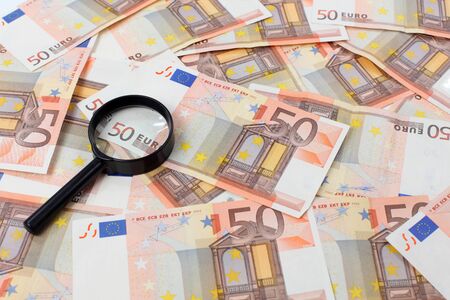 Fifty euro banknotes and a magnifying glass