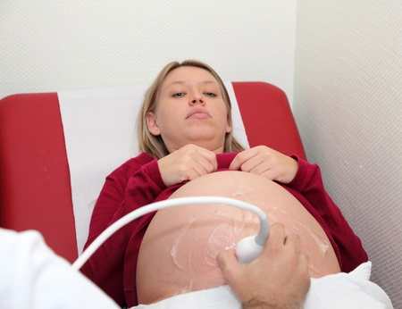 Pregnant woman getting ultrasound examination from doctorの写真素材