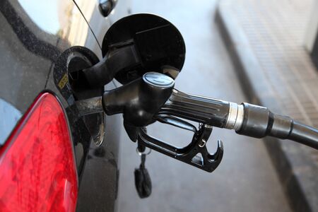 Gas station pump nozzle in the cars fuel tankの写真素材