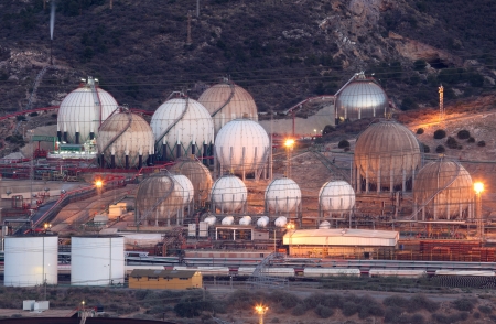 Storage tanks of an oil refinery illuminated in the eveningの写真素材