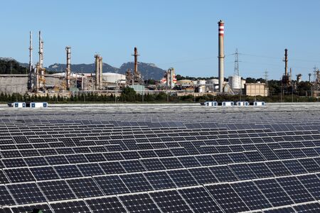 Solar power station with a oil refinery in the backgroundのeditorial素材