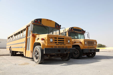 Two yellow school buses in a parking lot. Doha, Qatar, Middle East