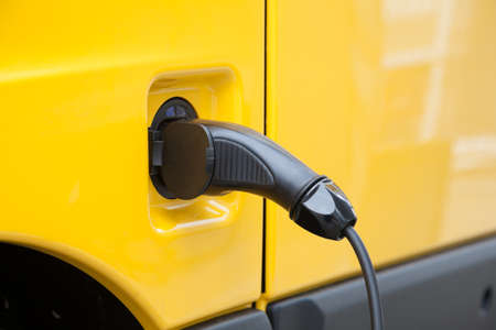 Plug and cable at a yellow electric carの写真素材