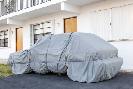 Car under a protective cover parked on the roadside in the cityの写真素材