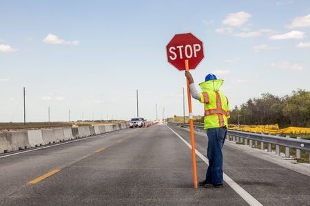 Road construction on the highway, Worker holds a stop sign to control the traffic