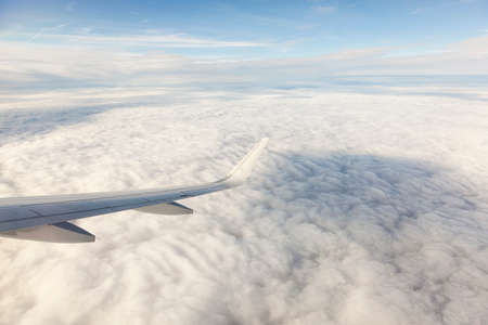 Wing of an airplane above beautiful clouds 