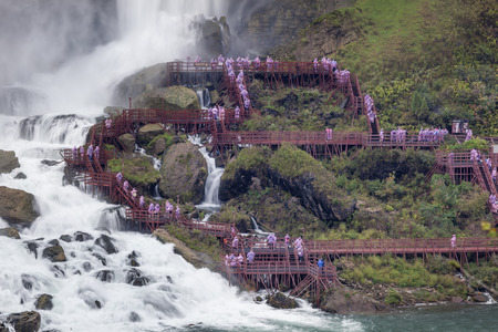Tourists climbing the stairs down to the Waterfalls viewing platform and getting wet. American Falls at the Niagara River, New York, USAの写真素材